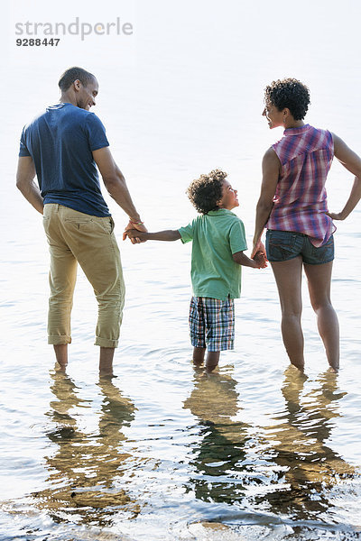 Eine Familie  Mutter  Vater und Sohn spielen am Ufer eines Sees.