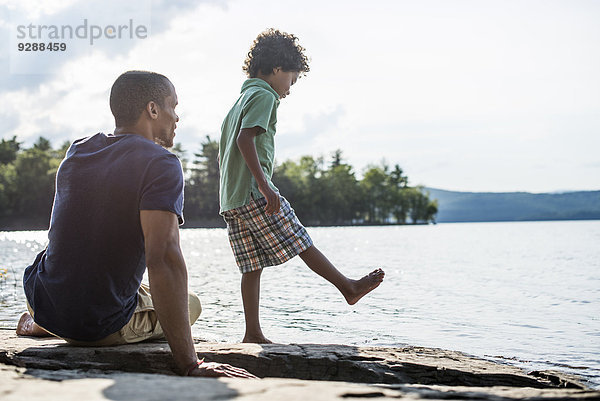 Ein Vater und Sohn an einem Seeufer im Sommer.