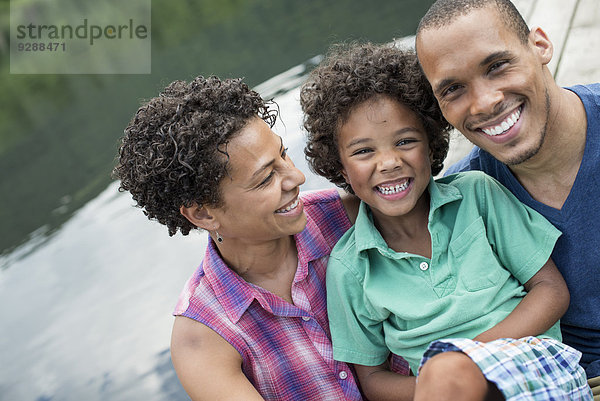 Eine Familie  Eltern und ein kleiner Junge  im Sommer an einem See.