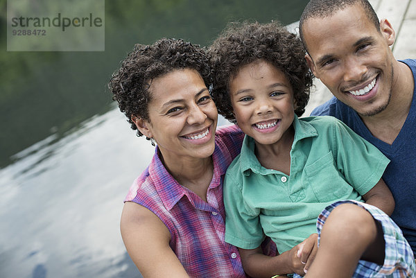 Eine Familie  Eltern und ein kleiner Junge  im Sommer an einem See.