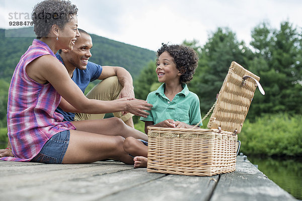 Eine Familie  die im Sommer ein Picknick an einem See macht.