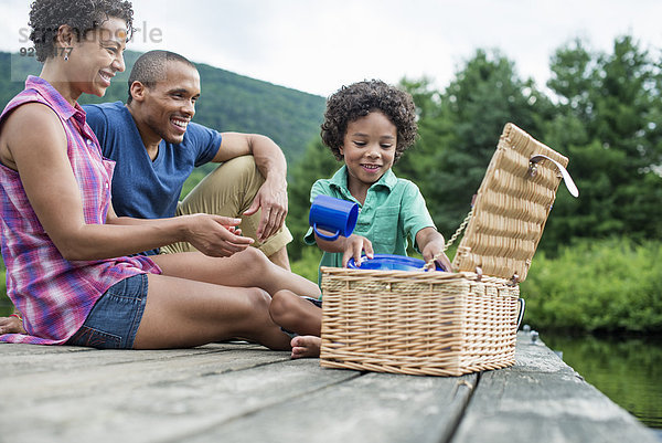 Eine Familie  die im Sommer ein Picknick an einem See macht.