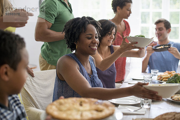 Ein Familientreffen  bei dem Männer  Frauen und Kinder an einem Esstisch sitzen und gemeinsam essen.