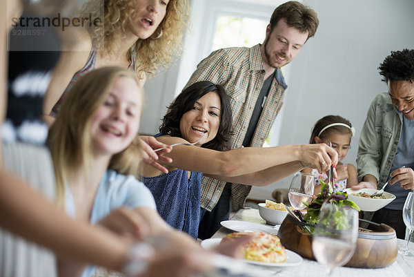 Ein Familientreffen zum Essen. Erwachsene und Kinder an einem Tisch.