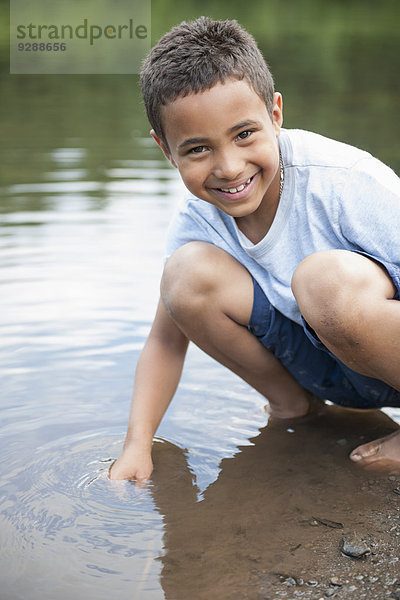Junge spielt an einem See.
