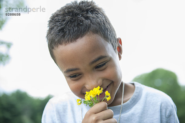 Junge lächelt und hält Blume.