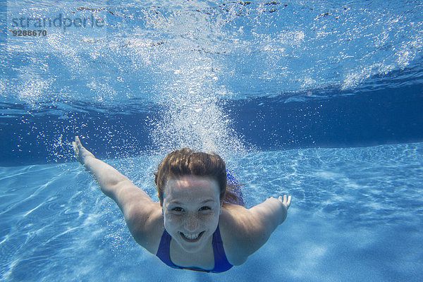 Ein junges Mädchen mit langen Haaren  das sich im Wasser auffächert und unter Wasser schwimmt.