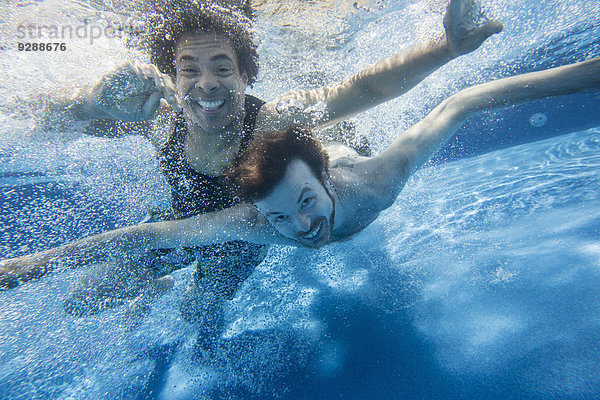 Zwei Männer schwimmen in einem Schwimmbad unter Wasser.