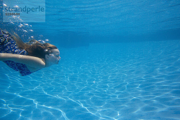 Ein Kind  das in einem Schwimmbad unter Wasser schwimmt.
