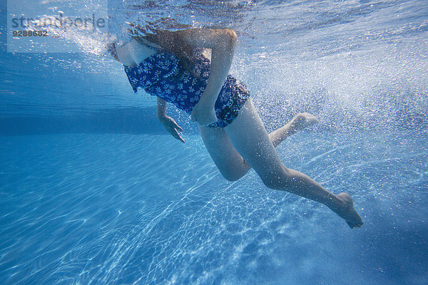 Ein Kind  das in einem Schwimmbad unter Wasser schwimmt.