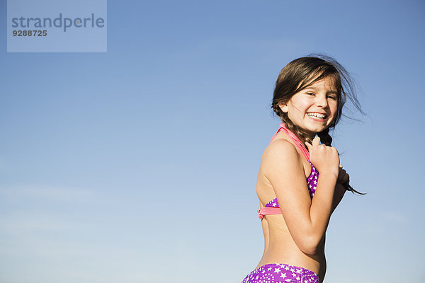 Ein kleines Kind im Bikini mit geflochtenen Haaren.