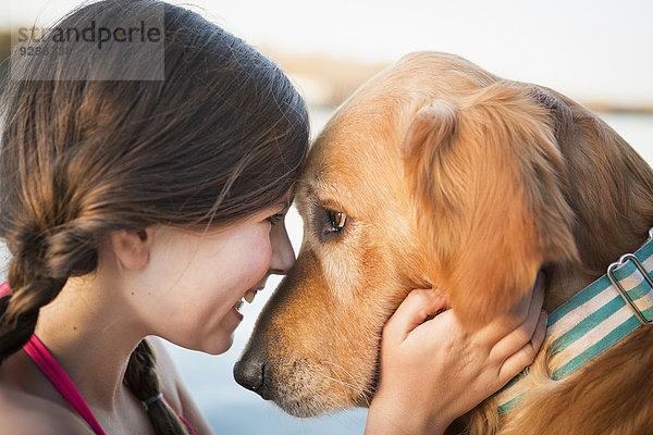 Ein junges Mädchen und ein Golden Retriever Hund  Nase an Nase.