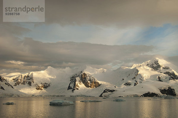 Dämmerung und flaches ruhiges Wasser vor der Küste einer Berglandschaft in der Antarktis.