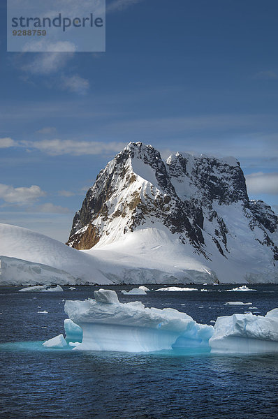 Eisberge  die im Wasser vor der felsigen Küste der Antarktis schwimmen.
