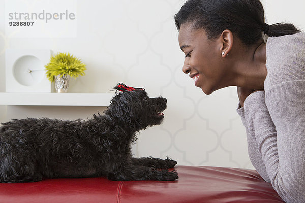 Ein junges Mädchen spielt mit ihrem kleinen schwarzen Haushund.