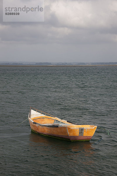 Ein kleines Holzboot  das im offenen Wasser vor der portugiesischen Küste vor Anker liegt.