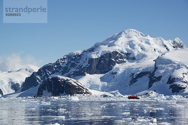 Ein kleines Boot  das auf dem Ozean zwischen Eisschollen vor der Küste einer Insel in der Antarktis treibt.