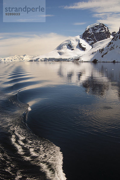 Berge und Schneelandschaft spiegeln sich im ruhigen Meerwasser im Südpolarmeer wider.