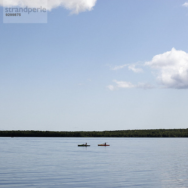 Zwei Personen in Kanus auf einem See