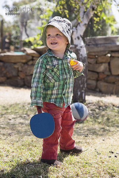 Glücklicher Junge mit Tischtennisschläger und Ball im Park