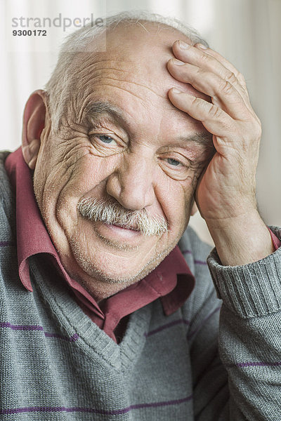 Porträt eines besorgten älteren Mannes mit Kopf in der Hand zu Hause