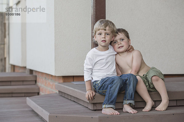 Volle Länge der Jungen  die auf der Veranda sitzen.