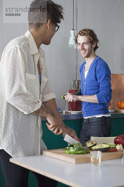Lächelnder Mann beim Kochen mit Freundin in der Küche