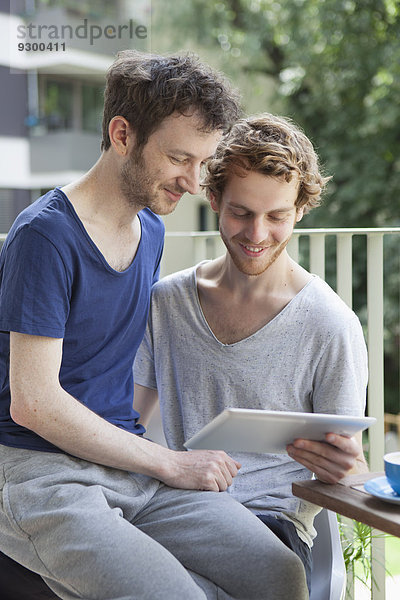 Schwules Paar mit digitalem Tablett auf der Veranda