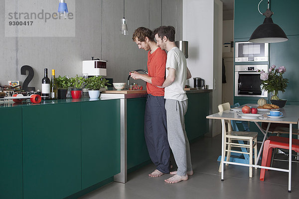 Durchgehende Seitenansicht des jungen schwulen Paares in der Küche