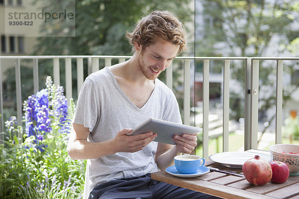 Lächelnder Mann mit digitalem Tablett auf der Veranda