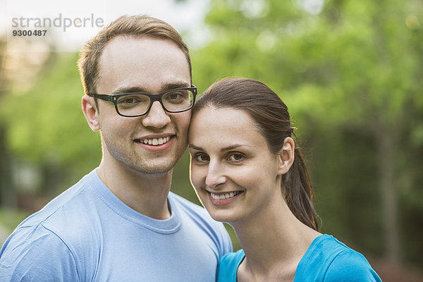 Porträt eines jungen Paares  das im Park lächelt.
