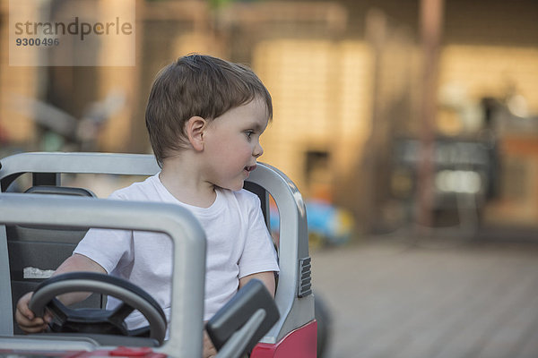 Süßer Junge im Spielzeugauto schaut weg.