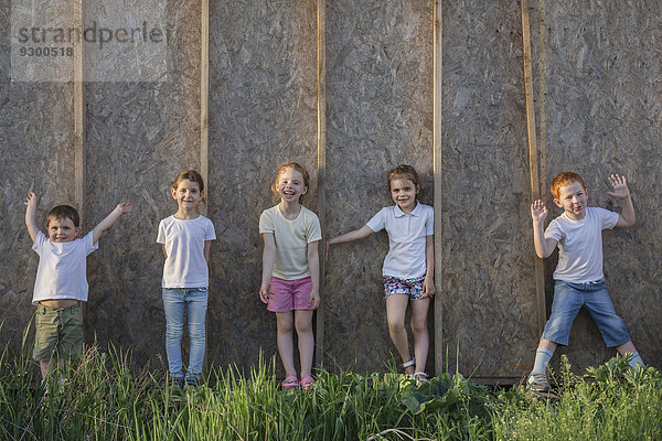 Porträt von spielenden Kindern  die im Park an der Wand stehen.