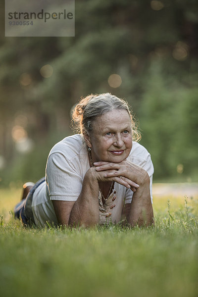 Nachdenkliche Seniorin im Park liegend