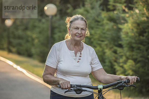 Porträt einer älteren Frau mit Fahrrad im Park