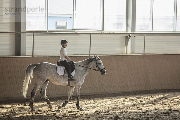 Seitenansicht des Jungen auf dem Pferd im Ausbildungsstall