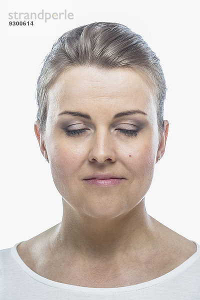 Mittlere erwachsene Frau mit geschlossenen Augen vor weißem Hintergrund