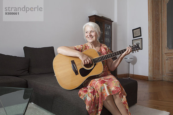 Seniorinnen beim Gitarrespielen im Wohnzimmer zu Hause