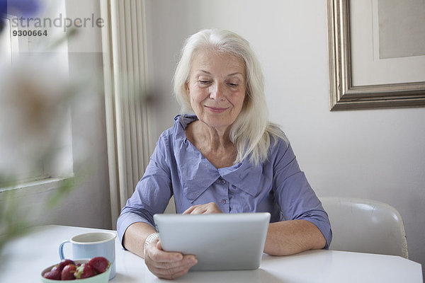 Seniorin mit digitalem Tablett zu Hause
