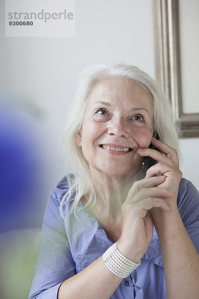 Glückliche Seniorenfrau  die zu Hause ans Handy geht