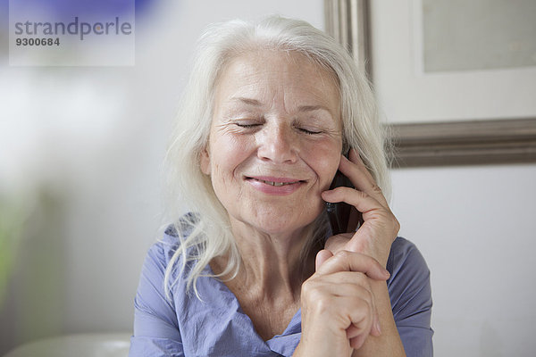 Entzückende Seniorin  die zu Hause ans Handy geht
