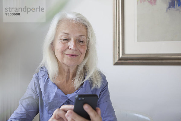 Senior Frau SMS über Smartphone zu Hause