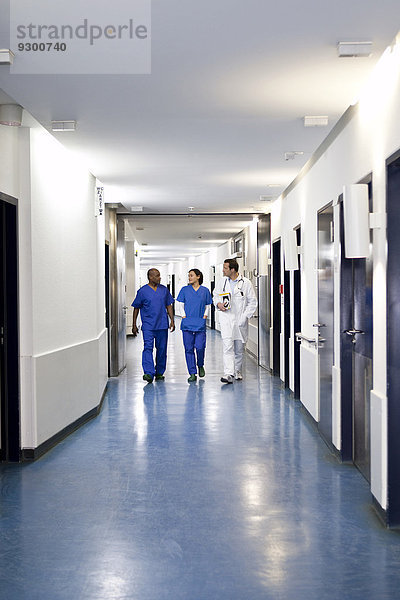 Drei Mediziner gehen gemeinsam einen Korridor in einem Krankenhaus entlang.
