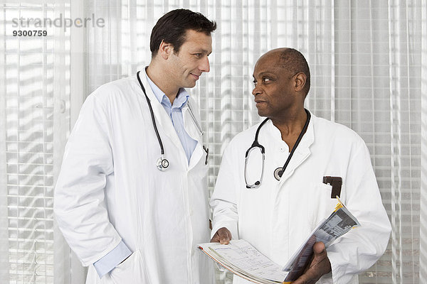 Zwei Ärzte in Laborkitteln beraten über eine Krankenakte