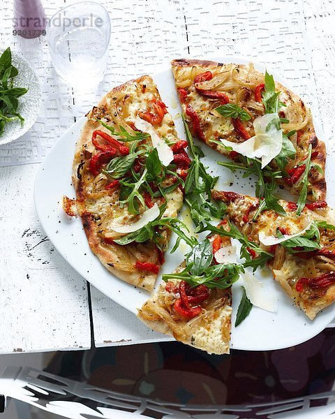 Teller mit geschnittener Vollkornpizza mit Kräutern  Gemüse und Parmesan