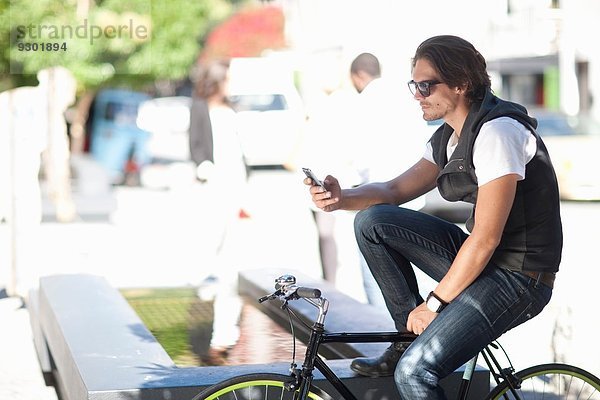 Mid Erwachsene männlich Radfahrer SMS auf Smartphone auf der Straße