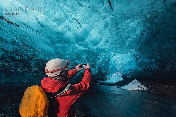 Mann fotografiert Eishöhle mit Smartphone  Vatnajokull Gletscher  Vatnajokull Nationalpark  Island