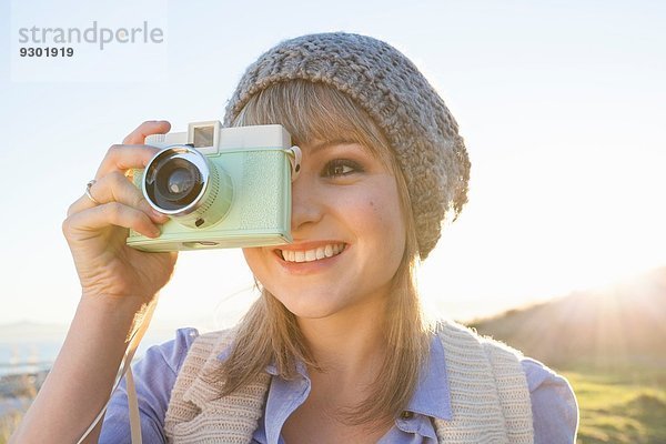 Junge Frau beim Fotografieren mit Kamera bei Sonnenuntergang