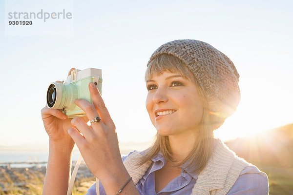 Junge Frau beim Fotografieren mit Kamera bei Sonnenuntergang