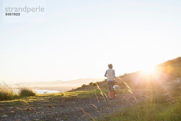 Junge Frau  die bei Sonnenuntergang auf dem Hügel läuft.